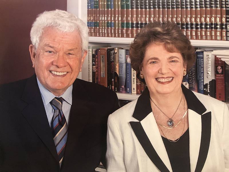 Dr. Desmond Berghofer and Dr. Geraldine Schwartz sit smiling in front of a bookshelf